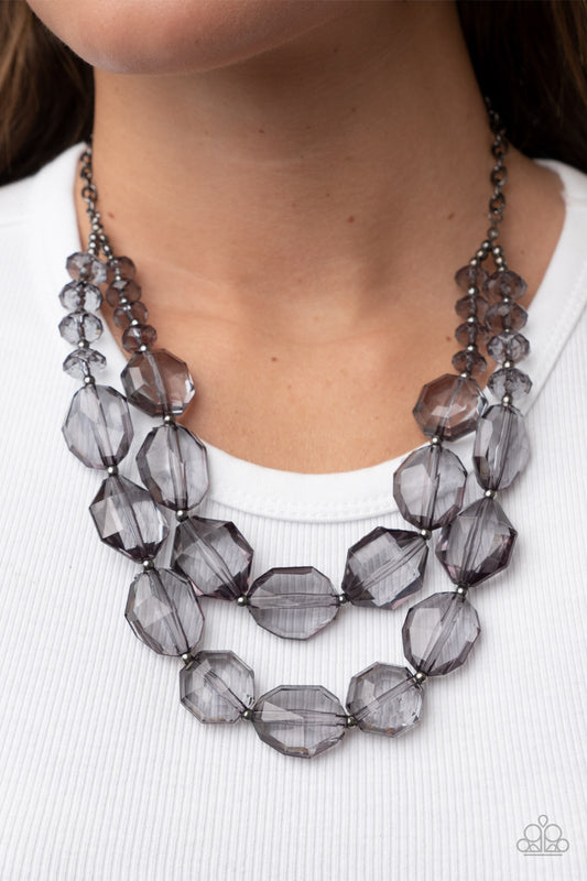 Icy Illumination Black Necklace - Paparazzi Accessories  Separated by dainty silver beads, an icy collection of oversized and faceted smoky gems are threaded along invisible wires below the collar, resulting in prismatic layers. Features an adjustable clasp closure.  Sold as one individual necklace. Includes one pair of matching earrings.