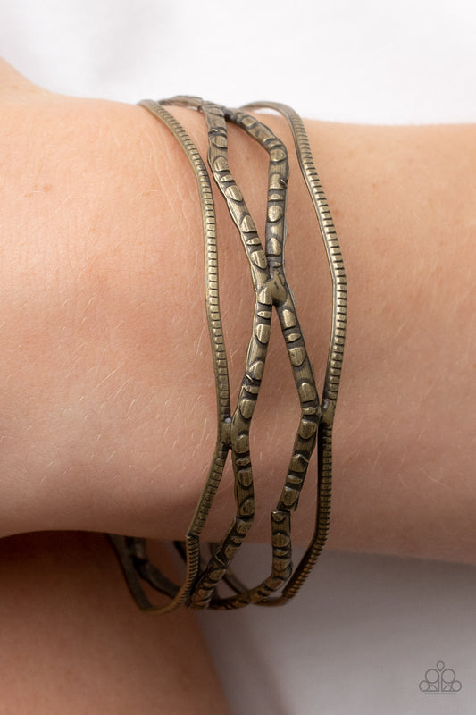 A Narrow ESCAPADE - Brass Item #P9BA-BRXX-059XX Textured and embossed in nature inspired patterns, rustic brass bars zigzag around the wrist as they stack into a wildly layered bangle.  Sold as one individual bracelet.