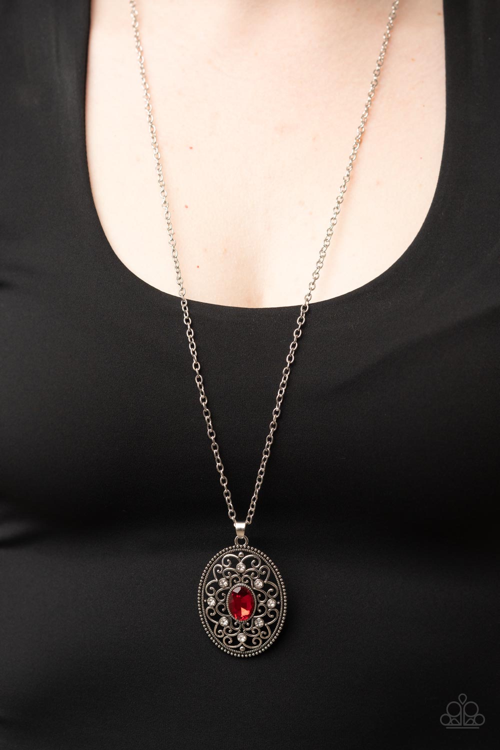 Sonata Swing - Red Item #P2RE-RDXX-234XX Dainty white rhinestones are sprinkled across silver vine-like filigree that whirls around an oval red gem center inside of a studded silver frame, resulting in a whimsical pendant at the bottom of a silver chain. Features an adjustable clasp closure.  Sold as one individual necklace. Includes one pair of matching earrings.