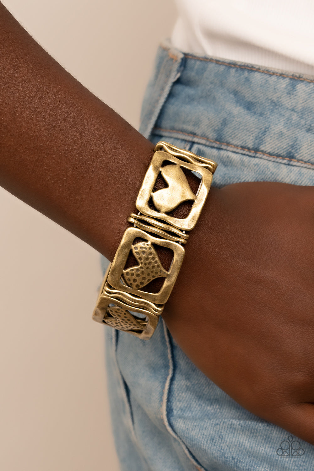 Legendary Lovers Brass Bracelet - Paparazzi Accessories  Encased in hammered brass frames, hammered brass hearts and brass hearts featuring a hammered dotted motif join pairs of wavy brass frames along stretchy bands around the wrist for a romantic flair.  Sold as one individual bracelet.