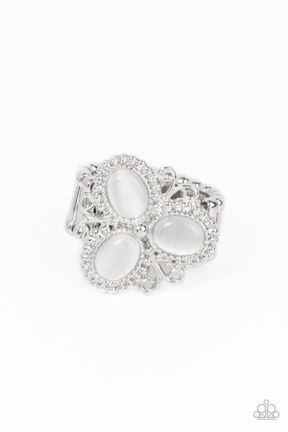 Bewitched Blossoms White Ring - Paparazzi Accessories  Three oval white cat's eye stones are encased in studded silver fittings featuring filigree accents, blooming into a magical floral centerpiece atop the finger. Features a stretchy band for a flexible fit.  Sold as one individual ring.