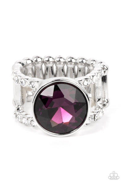 High Roller Sparkle Purple Ring - Paparazzi Accessories  A dramatically oversized brilliant purple solitaire gem, encased in a simple silver frame, sits atop rhinestone encrusted layered bands creating an unapologetically head-turning statement. Features a stretchy band for a flexible fit.  Sold as one individual ring.