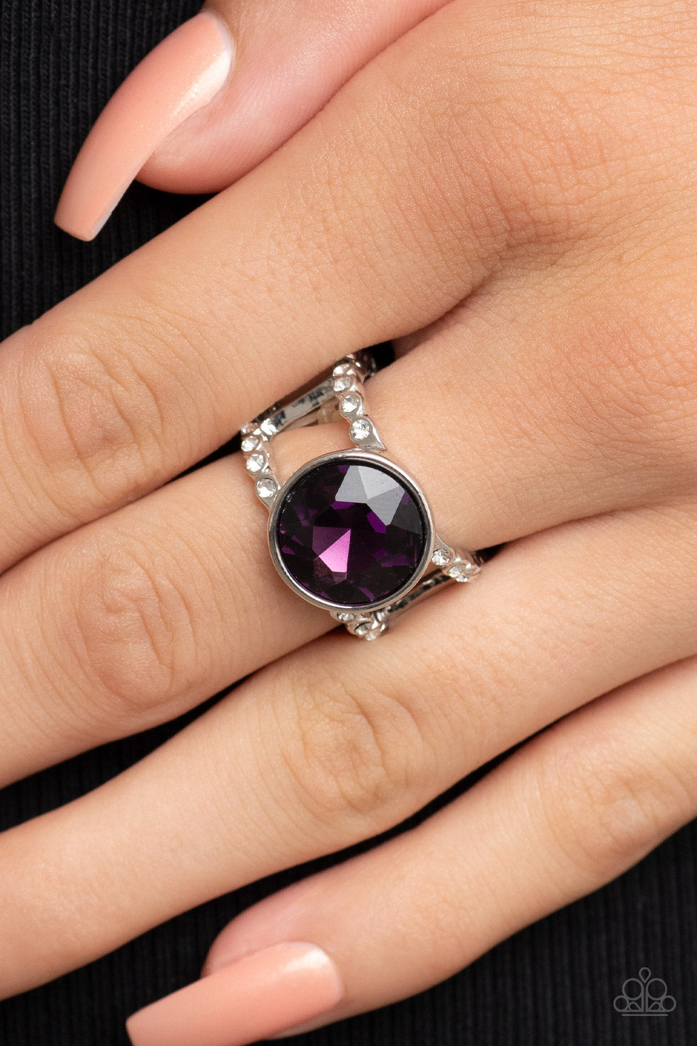 High Roller Sparkle Purple Ring - Paparazzi Accessories  A dramatically oversized brilliant purple solitaire gem, encased in a simple silver frame, sits atop rhinestone encrusted layered bands creating an unapologetically head-turning statement. Features a stretchy band for a flexible fit.  Sold as one individual ring.