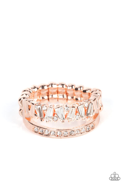 Fractal Fascination Rose Gold Ring - Paparazzi Accessories  Infused with a timeless band of white rhinestones, a dainty collection of trapezoidal cut white rhinestones staggers across the finger for a glamorously layered look. Features a dainty stretchy band for a flexible fit.  Sold as one individual ring.