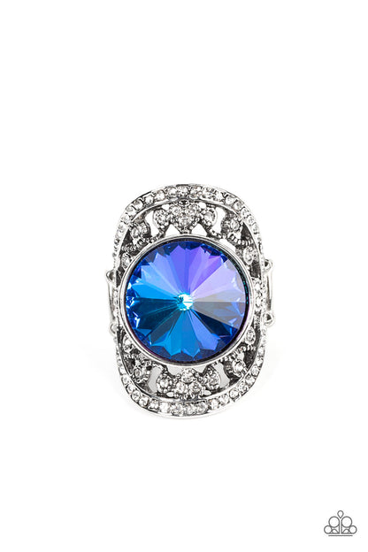 Galactic Garden Blue Ring - Paparazzi Accessories  A dramatically oversized, iridescent blue gem is pressed into the center of an oval silver frame dotted and bordered in glassy white rhinestones, resulting in a sparkly filigree-filled centerpiece atop the finger. Features a stretchy band for a flexible fit. Due to its prismatic palette, color may vary.  Sold as one individual ring.