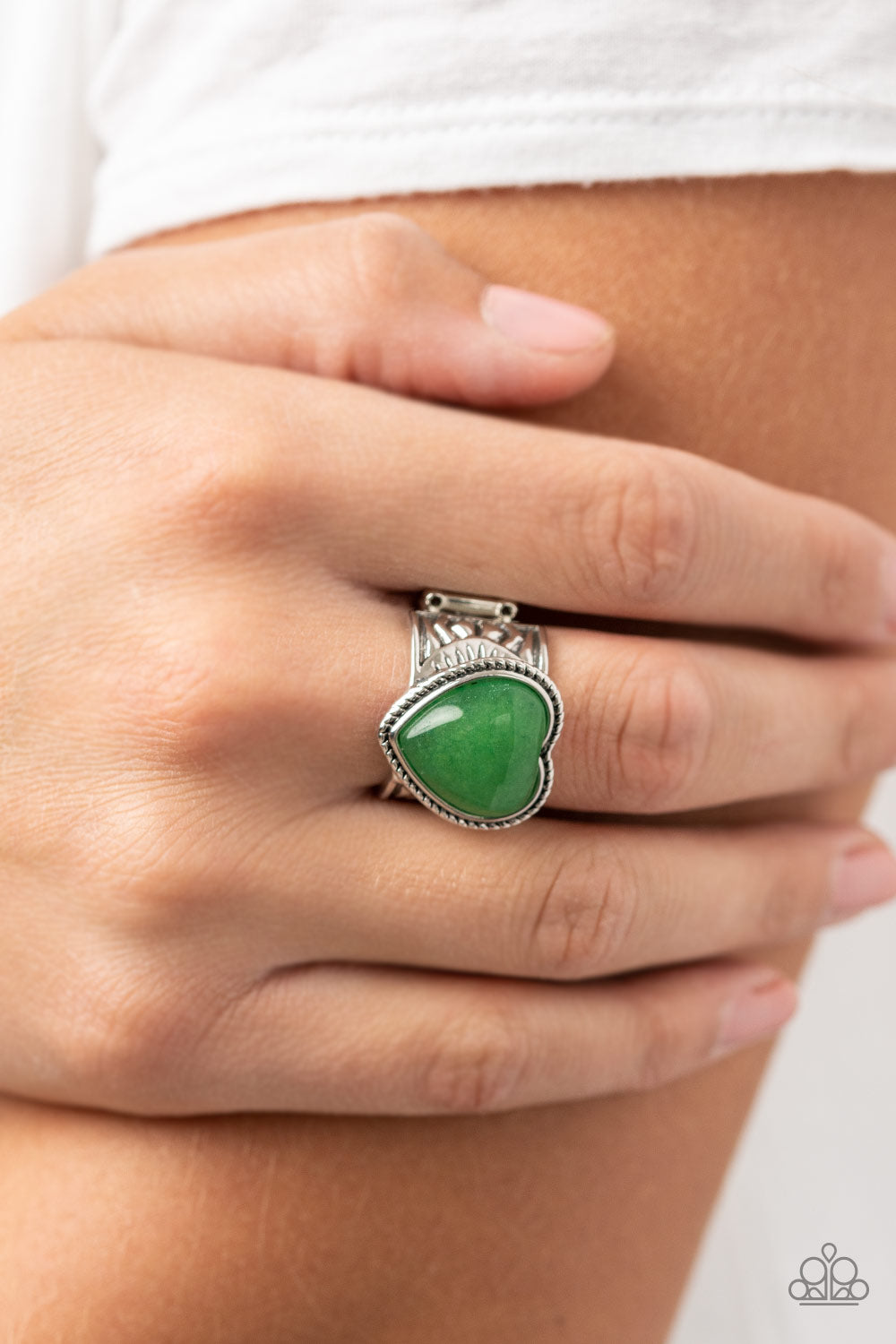Stone Age Admirer Green Ring - Paparazzi Accessories  A heart shaped jade stone adorns the center of a textured frame atop a thick silver band embossed in indigenous inspired details, resulting in an earthy pop of color atop the finger. Features a stretchy band for a flexible fit.  Sold as one individual ring.