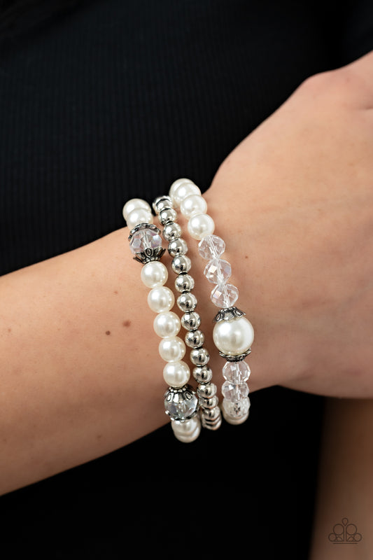 Positively Polished White Bracelet - Paparazzi Accessories  Stretchy pearl and silver beaded bracelets are adorned with ornate silver accents and glassy crystal-like beads, creating polished layers around the wrist.  Sold as one set of three bracelets.