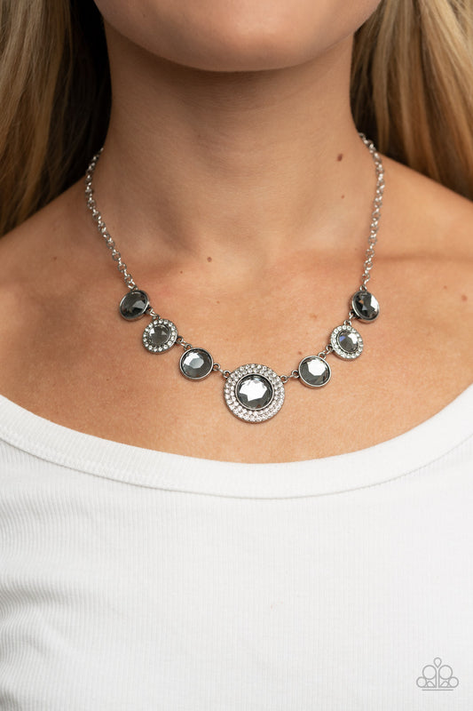 Extravagant Extravaganza Silver Necklace - Paparazzi Accessories  Oversized smoky gems alternate with matching gems bordered in rings of glassy white rhinestones below the collar, resulting in a spellbinding sparkle at the bottom of a classic silver chain. Features an adjustable clasp closure.  Sold as one individual necklace. Includes one pair of matching earrings.