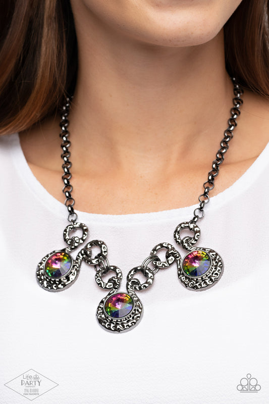 Hypnotized Multi Necklace - Paparazzi Accessories  Three dramatically oversized oil spill rhinestones are nestled into three textured gunmetal fittings that are connected by oval gunmetal rings, creating a brilliant statement piece. Features an adjustable clasp closure.  Sold as one individual necklace. Includes one pair of matching earrings. This Fan Favorite is back in the spotlight at the request of our 2021 Life of the Party member with Pink Diamond Access, NaKisha M.