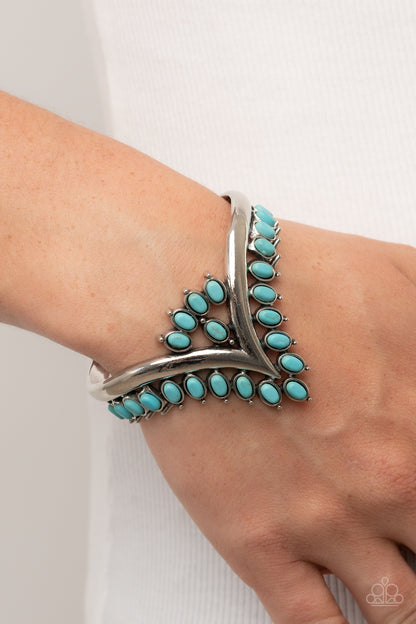 Teton Tiara Blue Cuff Bracelet - Paparazzi Accessories  Turquoise oval stones, encased in studded silver frames, line the edge of a daring V-shaped silver cuff. A gathering of turquoise stones adorns the center of the bracelet, adding a finishing touch to the rustically regal cuff.  Sold as one individual bracelet.