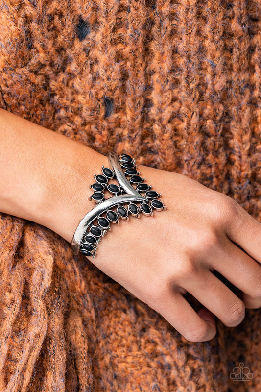 Teton Tiara Black Cuff Bracelet- Paparazzi Accessories   Black oval stones, encased in studded silver frames, line the edge of a daring V-shaped silver cuff. A gathering of black stones adorns the center of the bracelet, adding a finishing touch to the rustically regal cuff.  Sold as one individual bracelet.
