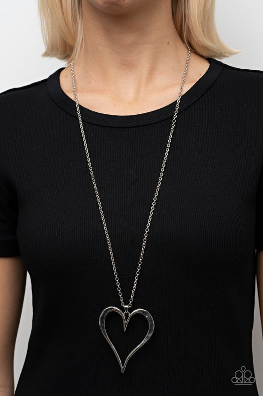 Hopelessly In Love Silver Necklace - Paparazzi Accessories  Featuring subtle hammered details, an oversized silver heart pendant swings from the bottom of a classic silver chain for a rustically romantic shimmer. Features an adjustable clasp closure.  Sold as one individual necklace. Includes one pair of matching earrings.