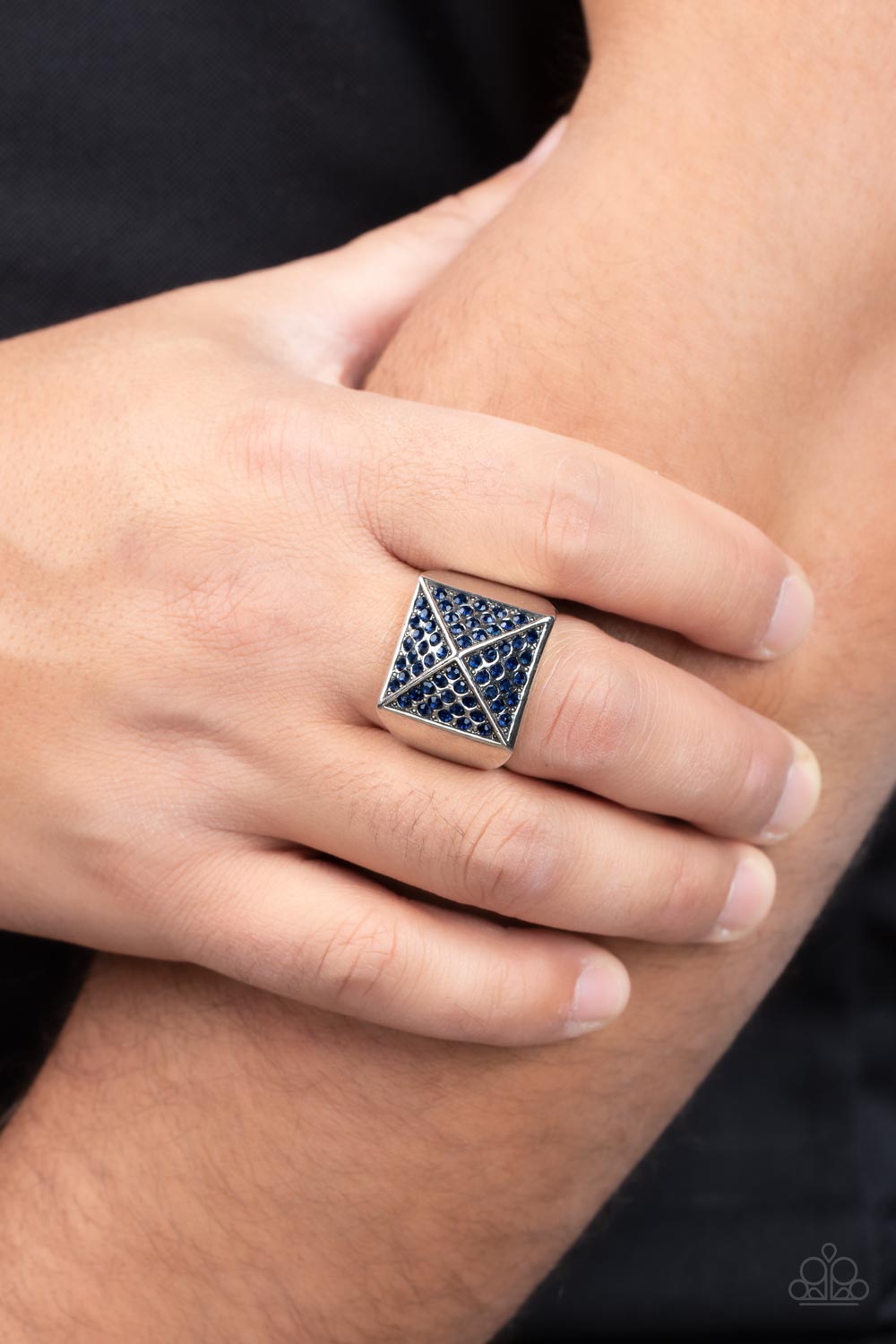 Pyramidal Powerhouse Blue Urban Ring - Paparazzi Accessories  Encrusted in glassy blue rhinestones, silver triangular frames build into a pyramidal centerpiece atop a thick silver band for a dauntless look. Features a stretchy band for a flexible fit.  Sold as one individual ring.