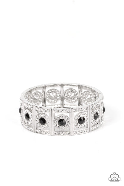 Ultra Upscale Black Bracelet - Paparazzi Accessories  A glassy black rhinestone is pressed into a ring of glitzy white rhinestones inside a rectangular silver frame dusted in dazzling white rhinestones. The timeless frames sparkle along stretchy bands around the wrist, resulting in a glamorously glittering centerpiece.  Sold as one individual bracelet.