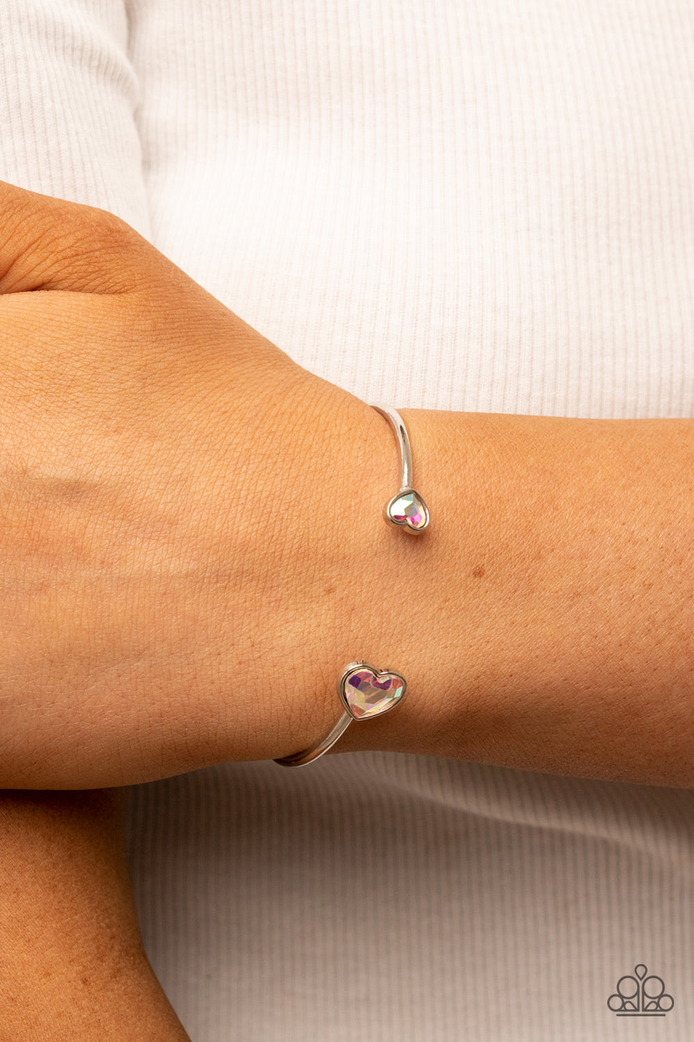 Unrequited Love Iridescent Heart Cuff Bracelet - Paparazzi Accessories  Enhanced with iridescent rhinestones, two silver hearts adorn the ends of a silver band that curls around the wrist for a flirtatious open-faced style cuff.  Sold as one individual bracelet.