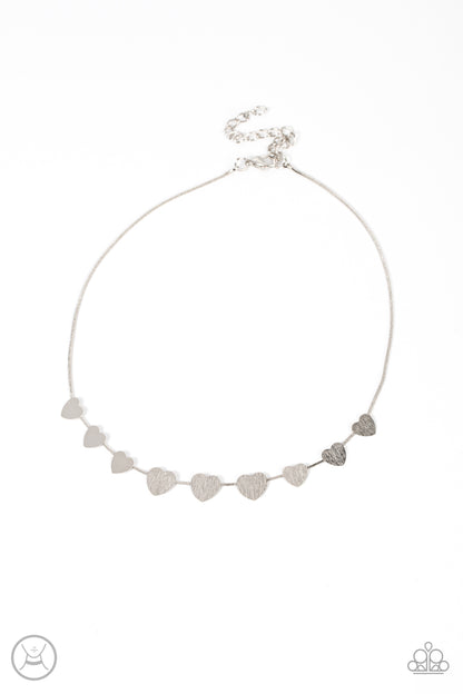Dainty Desire Silver Choker Necklace - Paparazzi Accessories  Delicately scratched in shimmer, a dainty collection of flat silver heart frames gradually increases in size along a shiny silver snake chain around the neck for a flirtatious fashion. Features an adjustable clasp closure.  Sold as one individual choker necklace. Includes one pair of matching earrings.