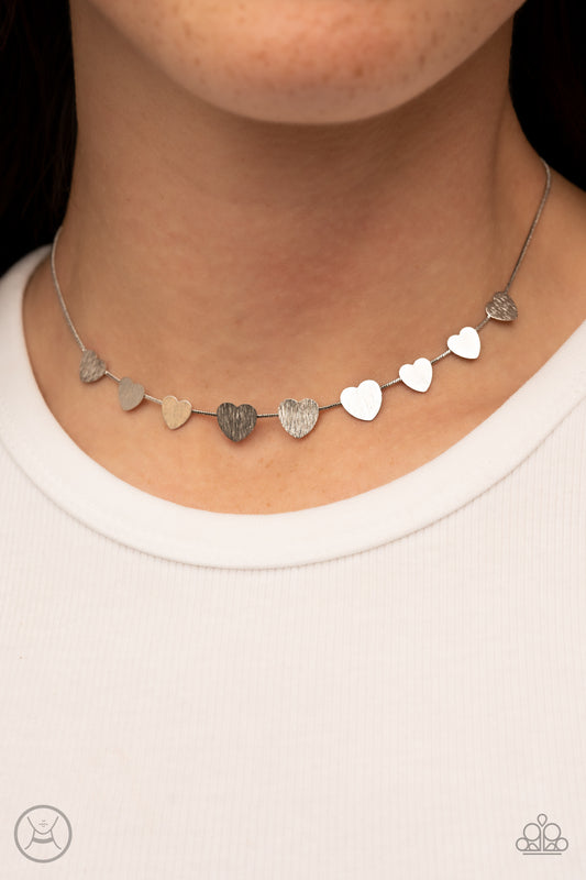 Dainty Desire Silver Choker Necklace - Paparazzi Accessories  Delicately scratched in shimmer, a dainty collection of flat silver heart frames gradually increases in size along a shiny silver snake chain around the neck for a flirtatious fashion. Features an adjustable clasp closure.  Sold as one individual choker necklace. Includes one pair of matching earrings.