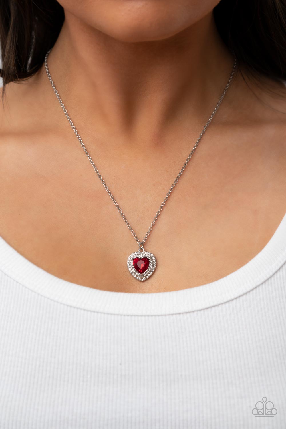 Taken with Twinkle Red Necklace - Paparazzi Accessories  Bordered in stacked rows of glassy white rhinestones, a fiery red heart shaped gem sparkles at the center of a dainty silver chain for a flirtatious fashion. Features an adjustable clasp closure.  Sold as one individual necklace. Includes one pair of matching earrings.
