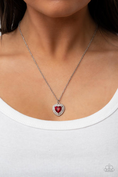 Taken with Twinkle Red Necklace - Paparazzi Accessories  Bordered in stacked rows of glassy white rhinestones, a fiery red heart shaped gem sparkles at the center of a dainty silver chain for a flirtatious fashion. Features an adjustable clasp closure.  Sold as one individual necklace. Includes one pair of matching earrings.