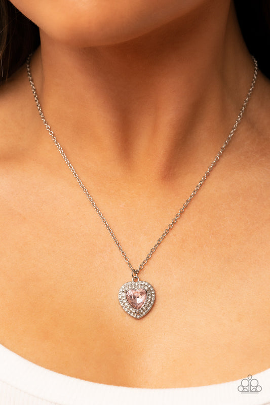 Taken with Twinkle Pink Heart Necklace - Paparazzi Accessories  Bordered in stack rows of glassy white rhinestones, a twinkly pink heart shaped gem sparkles at the center of a dainty silver chain for a flirtatious fashion. Features an adjustable clasp closure.  Sold as one individual necklace. Includes one pair of matching earrings.