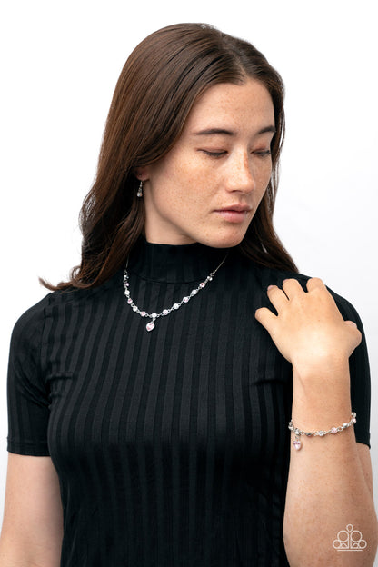 True Love Trinket Pink Necklace & Bracelet Set - Paparazzi Accessories A pink rhinestone heart charm dances from a strand of white and pink rhinestones, resulting in a flirtatious sparkle below the collar and around the wrist. Sold as one individual necklace. Includes one matching bracelet. Get The Complete Look! Bracelet: "Truly Lovely - Pink"