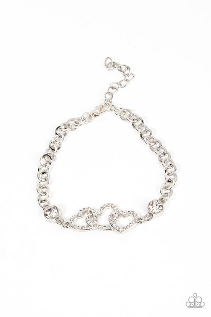Desirable Dazzle White Bracelet - Paparazzi Accessories  White rhinestone dotted hearts delicately interlock between two white rhinestone fittings, creating heart-pounding sparkle atop the wrist. Features an adjustable clasp closure.  Sold as one individual bracelet.