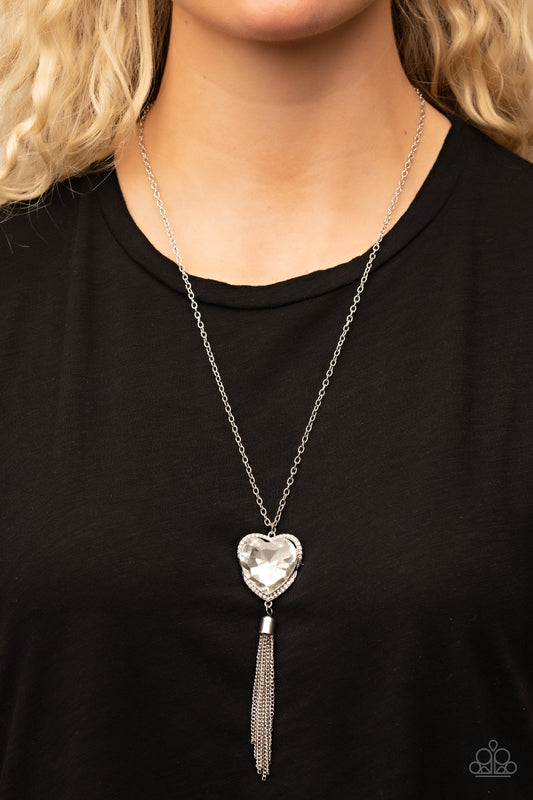 Finding My Forever White Heart Necklace - Paparazzi Accessories  Bordered in a ribbon of glassy white rhinestones, an oversized white heart-shaped gem seemingly floats at the bottom of an extended silver chain. A shimmery silver chain tassel dances from the bottom of the sparkly pendant for a flirtatious finish. Features an adjustable clasp closure.  Sold as one individual necklace. Includes one pair of matching earrings.