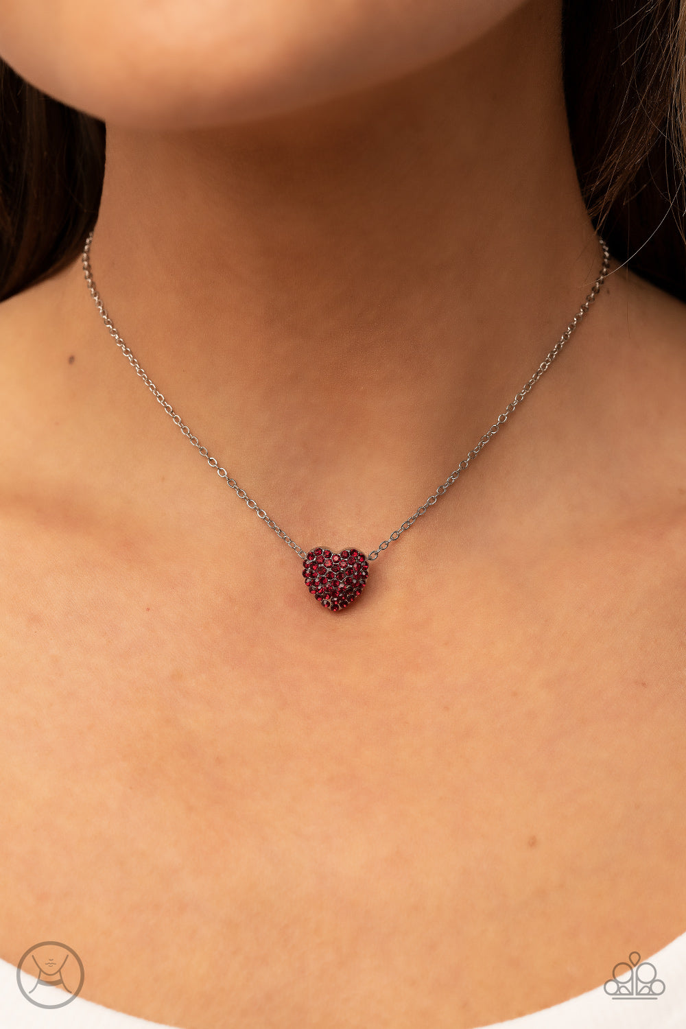 Twitterpated Twinkle Red Necklace - Paparazzi Accessories  Encrusted in fiery red rhinestones, a dainty heart frame sparkles along a dainty silver chain around the neck for a flirty finesse. Features an adjustable clasp closure.  Sold as one individual choker necklace. Includes one pair of matching earrings.
