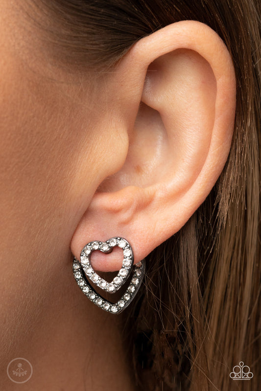 Ever Enamored Black Jacket Earring - Paparazzi Accessories  A dainty gunmetal heart dotted in glassy white rhinestones flirtatiously attaches to a double-sided post, while a slightly larger white rhinestone encrusted gunmetal heart peeks out beneath the ear for a romantic finish. Earring attaches to a standard post fitting.  Sold as one pair of double-sided post earrings.