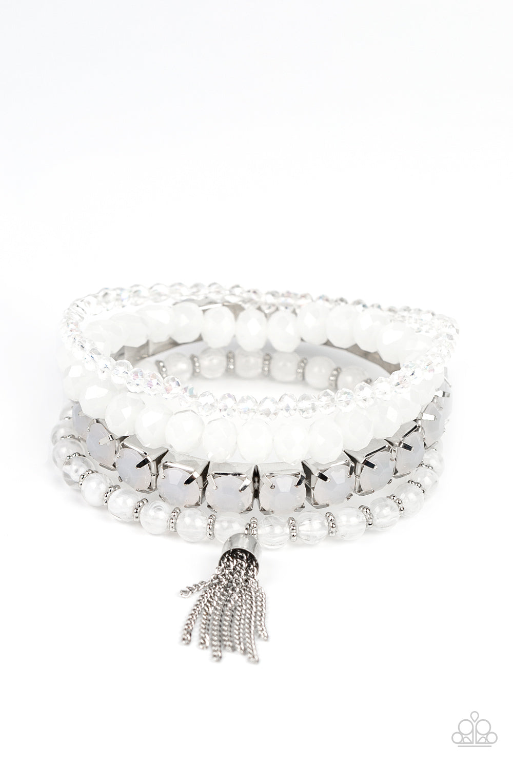 Day Trip Trinket White Bracelet - Paparazzi Accessories  Pinched in silver fittings, a stretchy band of dewy white beads joins mismatched strands of cloudy and glassy white crystal-like and stretchy bracelets around the wrist. A single silver chain tassel dances from the crystalline compilation for a final flirty finesse.  Sold as one set of four bracelets.