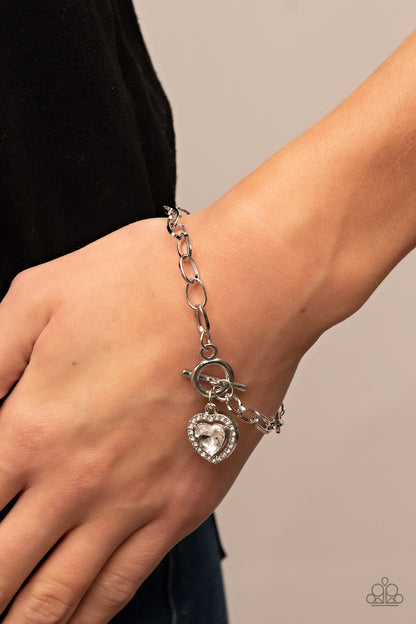 Till DAZZLE Do Us Part White Bracelet - Paparazzi Accessories  Bordered in glassy white rhinestones, a white heart shaped gem sparkles from a toggle closure at the center of an oval silver linked chain for a flirtatious fashion around the wrist. Features a toggle closure.  Sold as one individual bracelet.