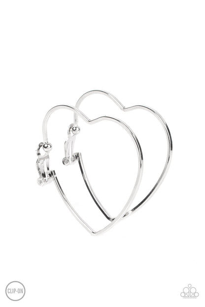 Harmonious Hearts Silver Clip-On Earring - Paparazzi Accessories  A glistening silver bar delicately curves into an oversized heart frame, resulting in a heart-stopping shimmer. Earring attaches to a standard clip-on fitting.  Sold as one pair of clip-on earrings.