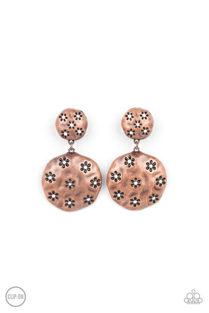 Industrial Fairytale Copper Clip-On Earring - Paparazzi Accessories  Dotted with dainty opal rhinestone centers, an antiqued floral pattern is stamped across the fronts of two hammered copper discs that delicately connect into a rustic lure. Earring attaches to a standard clip-on fitting.  Sold as one pair of clip-on earrings.