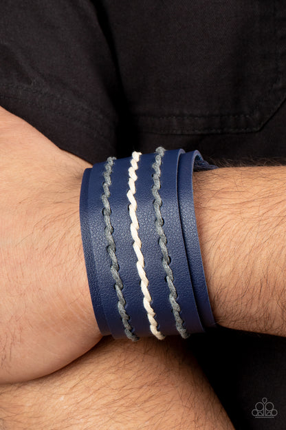 Real Ranchero Blue Wrap Bracelet - Paparazzi Accessories Item #P9UR-BLXX-229XX Three rows of gray and white cording are laced down the center of a blue leather band that is studded in place across the front of a thick blue leather band, resulting in a rustic pop of color around the wrist. Features an adjustable snap closure.  Sold as one individual bracelet.