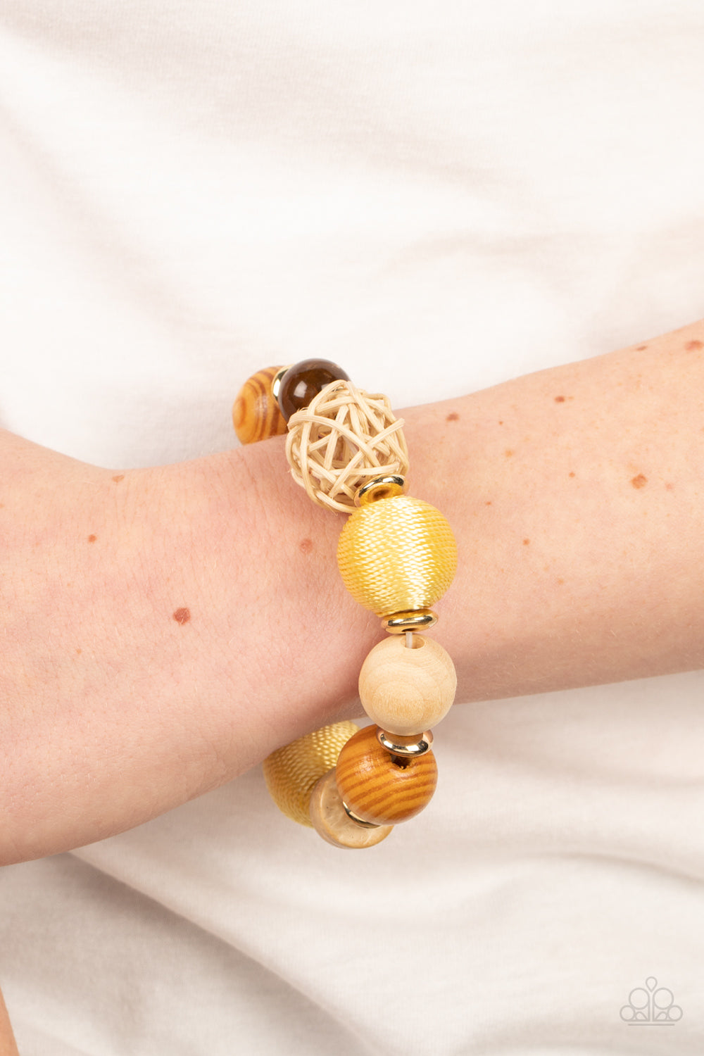 Happily Homespun Yellow Bracelet - Paparazzi Accessories  Infused with a single rattan sphere, a mismatched collection of oversized wooden beads, yellow thread wrapped beads, dainty gold accents, and glassy brown beads are threaded along stretchy bands around the wrist for a homespun vibe.  Sold as one individual bracelet.
