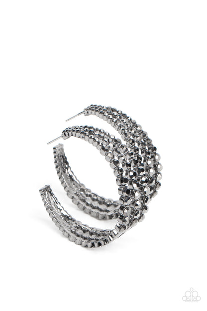 Cosmopolitan Cool Black Hoop Earring - Paparazzi Accessories  Cascading layers of smoldering hematite rhinestones plunge into flattened gunmetal plates creating a stunning eye-catching hoop earring. Earring attaches to a standard post fitting. Hoop measures approximately 2" in diameter.  Sold as one pair of hoop earrings.