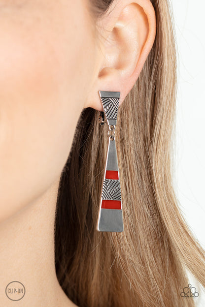 Safari Seeker Red Clip-On Earring - Paparazzi Accessories  Etched in sections of slanted textile-like patterns, two antiqued triangular silver frames link into an edgy lure. The lowermost frame is painted in rows of shiny red accents, adding a fiery pop of color to the adventurous display. Earring attaches to a standard clip-on fitting.  Sold as one pair of clip-on earrings.