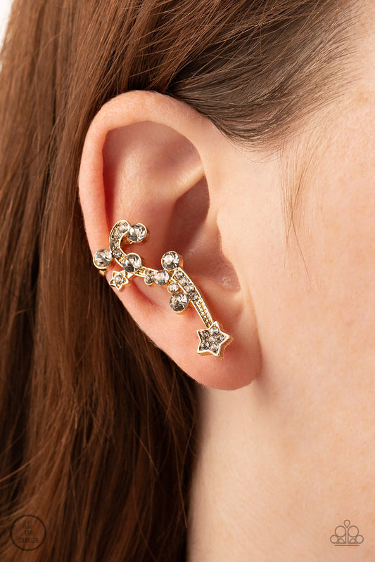 Astral Anthem Gold Star Ear Crawler Earring - Paparazzi Accessories  Dotted with dainty gold studs, glittery white rhinestones, a white rhinestone dotted star, and a glittery ribbon streams out from a white rhinestone dotted gold star like a shooting star as it climbs the ear. Earring attaches to a standard post fitting. Features a clip-on fitting at the top for a secure fit.  Sold as one pair of ear crawlers.