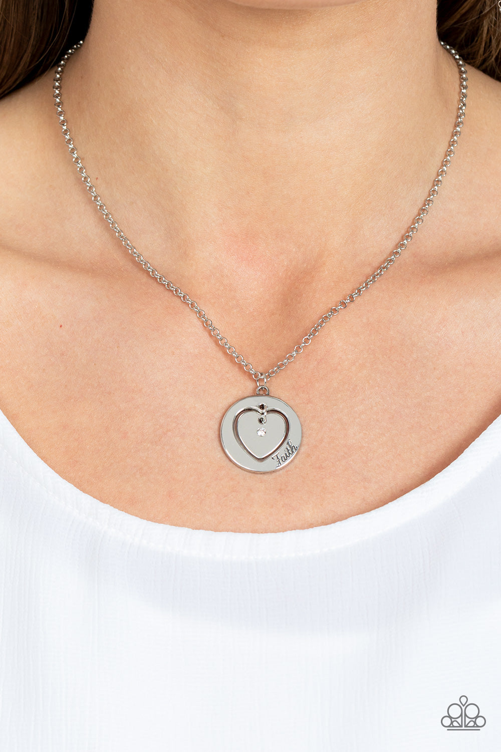 Heart Full of Faith White Necklace - Paparazzi Accessories  Dotted with a dainty white rhinestone, a silver heart charm swings freely inside of a heart-cutout silver frame. Stamped in the word, "Faith," the inspirational pendant falls just below the collar for a sentimental finish. Features an adjustable clasp closure.  Sold as one individual necklace. Includes one pair of matching earrings.