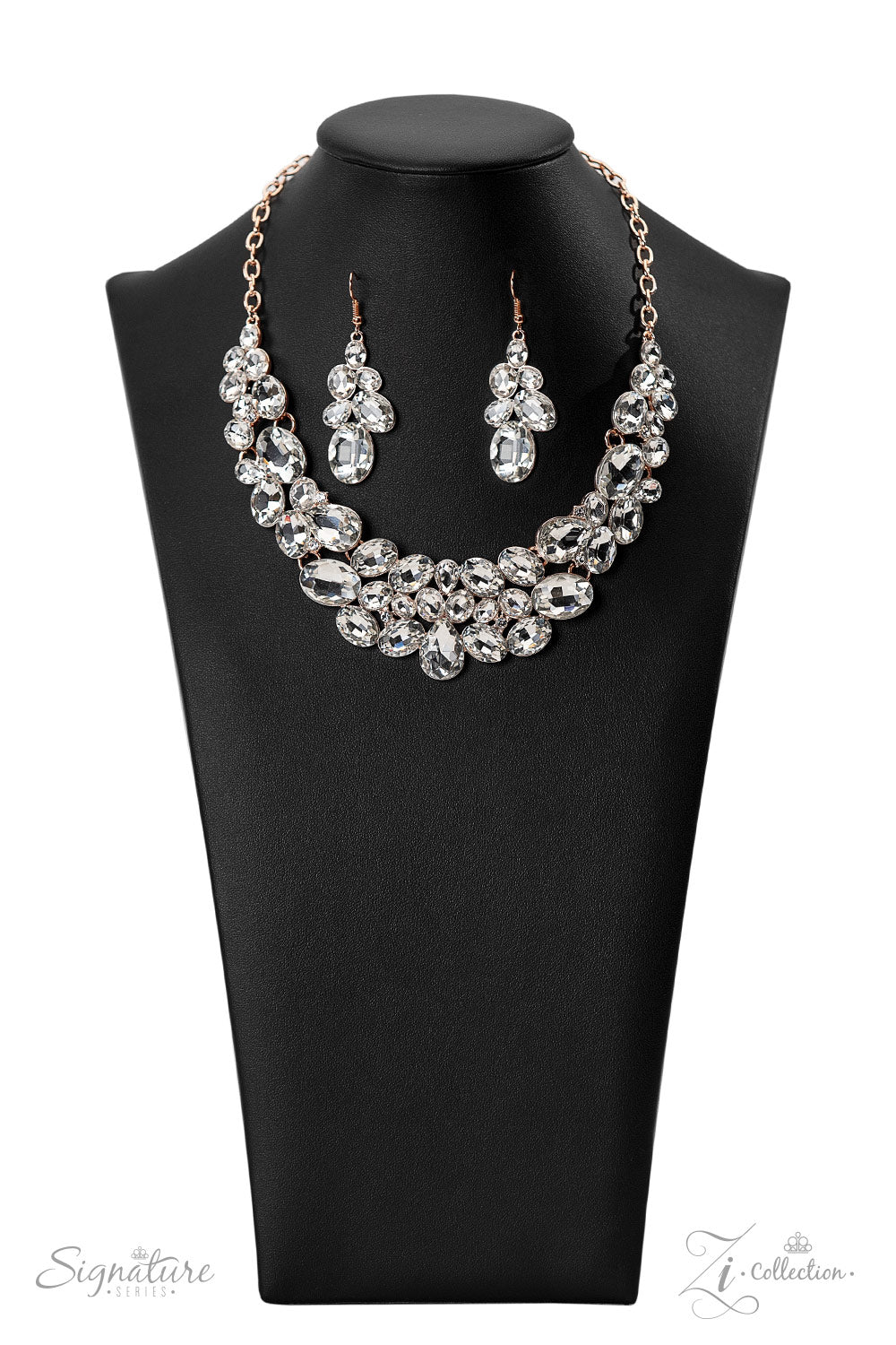 The Jenni 2022 Zi Collection Necklace - Paparazzi Accessories  Oversized white rhinestones with exaggerated faceted surfaces gather into glittery clusters along the collar. A teardrop-shaped gem sits front-and-center, inviting the eye to explore the scattered shapes throughout the design. Refined sparkle radiates from every angle, as the rose gold finish of the chain and fittings emit a cozy glow. Features an adjustable clasp closure.  Sold as one individual necklace. Includes one pair of matching earrings.