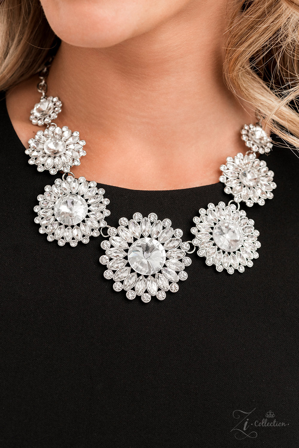 Oversized classic white rhinestones are encircled by majestic marquise-cut rhinestones in the same radiant finish, creating a collection of stunning floral frames. Smaller white rhinestones fall in between each gorgeous marquise-cut petal, magnifying the shimmer emitted by the dramatically faceted surfaces of each piece. The glittery flowers increase in size as they link together along the neckline, leading to the largest frame at the center in a twinkling finish. Features an adjustable clasp closure.
