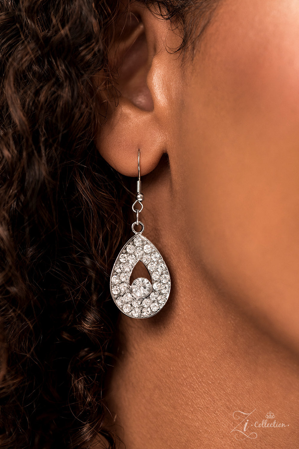 Silver, teardrop-shaped frames are stacked on-point below airy marquise cutouts, creating a subtle figure-eight. The hourglass shapes are threaded along invisible wires, falling into place alongside diamond-shaped frames, created by artfully aligned, smaller, teardrop silhouettes. Glittery rhinestones encrust the larger teardrop-shaped frames, with solitaire rhinestones dotting the others; the result is a blinding display of irresistible shimmer that leads to a heart-stopping centerpiece.