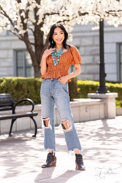 Strands of oversized silver chain links and rounded box chain in the same metallic sheen, drape into dramatic layers across the chest, creating a boisterous collision of texture. Smooth turquoise stones, chiseled into large, flat squares, circles, and rectangles, dance along the bulky silver chains, bringing vibrant splashes of color to the design. Finally, floral appliqués in an antiqued silver finish decorate the surfaces of some of the turquoise stones.