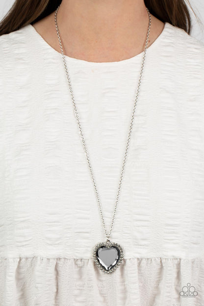 Prismatically Twitterpated Silver Necklace - Paparazzi Accessories  Bordered in glassy white rhinestones, an oversized smoky heart gem sparkles from the bottom of an extended silver chain for a flirty finish. Features an adjustable clasp closure.  Sold as one individual necklace. Includes one pair of matching earrings.