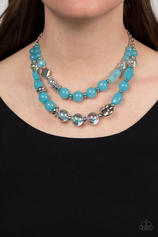 Mere Magic Blue Necklace - Paparazzi Accessories  Featuring various shapes and finishes, a mismatched assortment of silver, iridescent, opaque Waterspout beads have been threaded along invisible wires below the collar, creating ethereal layers. Features an adjustable clasp closure. Due to its prismatic palette, color may vary.  Sold as one individual necklace. Includes one pair of matching earrings.