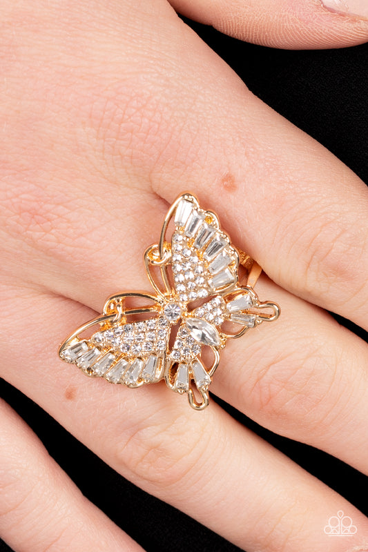 Fearless Flutter Gold Butterfly Ring - Paparazzi Accessories  Sparkling with round, teardrop, and emerald cut white rhinestones, a gold butterfly fearlessly flutters atop the finger for a statement-making finish. Features a stretchy band for a flexible fit.  Sold as one individual ring.