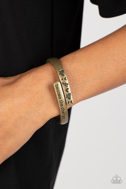 WINGS of Change Brass Hinge Bracelet - Paparazzi Accessories  Antiqued brass bars curve and overlap around the wrist, creating a stacked design. One brass bar is stamped with the phrase, "become the change," while the other features engraved butterfly silhouettes in an inspiring finish. Features a hinged closure.  Sold as one individual bracelet.