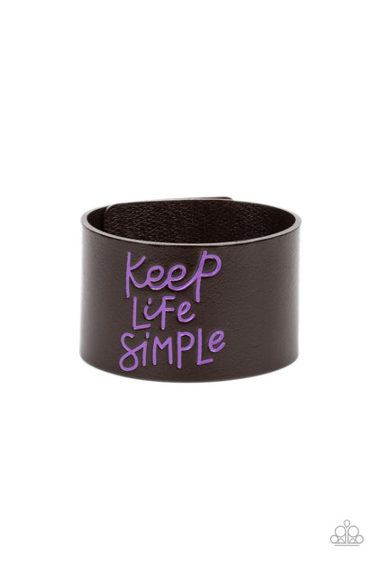Simply Stunning Purple Wrap Bracelet - Paparazzi Accessories  A thick band of dark brown leather is stamped in the phrase, "Keep Life Simple," in purple script. The playful font emphasizes the lighthearted message as the band wraps around the wrist in a casual finish. Features an adjustable snap closure.  Sold as one individual bracelet.