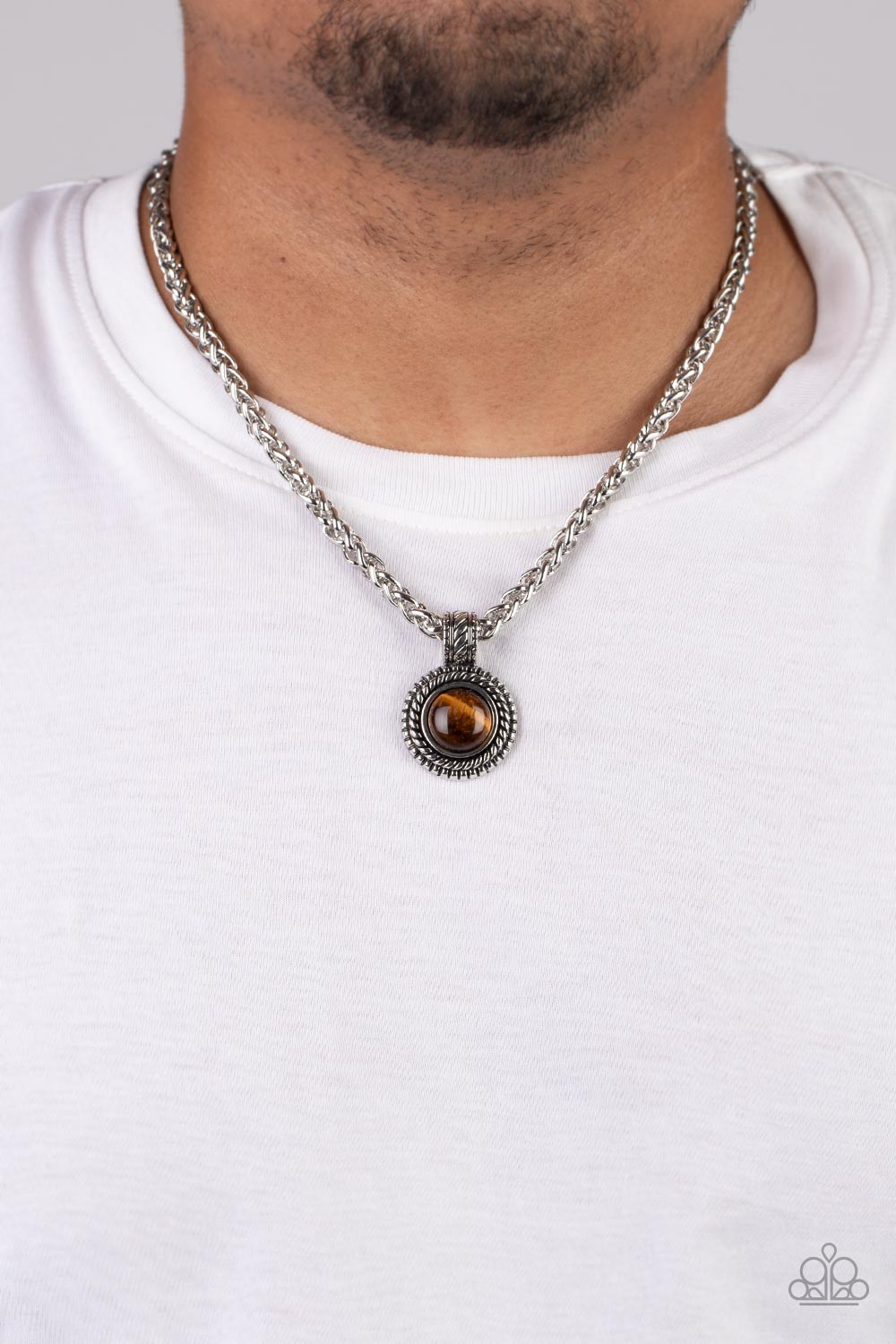 Pendant Dreams Brown Urban Necklace - Paparazzi Accessories   A textured silver frame spins around a tiger's eye stone center, creating a tranquil statement piece. The reflective pendant is anchored by a textured silver fixture, adding eye-catching dimension as the pendant slides along a thick strand of silver wheat chain. Features an adjustable clasp closure. As the stone elements in this piece are natural, some color variation is normal.  Sold as one individual necklace.
