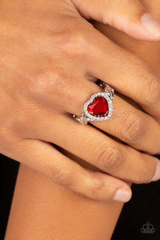 Committed to Cupid Red Ring - Paparazzi Accessories  A faceted red heart gem is pressed into a silver heart frame studded with dainty white crystals for a romantic centerpiece atop the finger. Textured twists dotted with similar dainty crystals climb up the sides of the ring for additional sparkle. Features a dainty stretchy band for a flexible fit.  Sold as one individual ring.